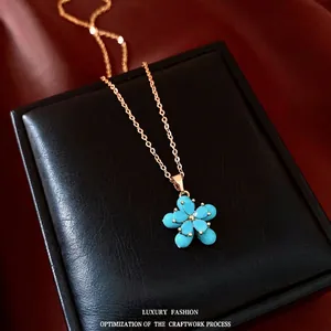 Elegante 18 Karat vergoldete Halskette mit blauem Blumenanhänger auf Schmuckschatulle