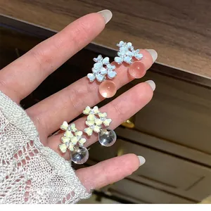 Elegant flower stud earrings with translucent beads shown in a hand-held close-up view.