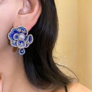 Detailed close-up of vintage blue crystal flower earrings with pearl and teardrop accents.