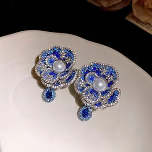 Macro detail of vintage blue crystal flower earrings with central pearl and silver needles
