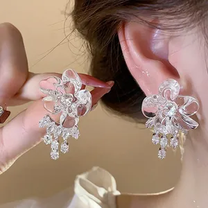 Detailed view of elegant resin flower stud earrings with sparkling crystal tassels on ear.