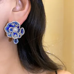 Detailed view of a vintage flower earring featuring a pearl center and blue crystals on the ear.
