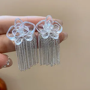 Detailed macro view of transparent resin flower earrings with silver chain tassels