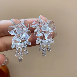 Close-up of elegant resin flower earrings with sparkling dangling zircon tassels.