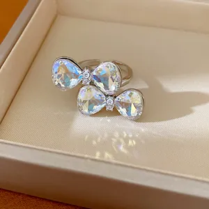Close-up of crystal bow open ring reflecting colorful light in a beige jewelry box
