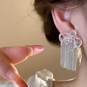 Close-up detail of elegant resin flower stud earrings featuring long silver tassel chains
