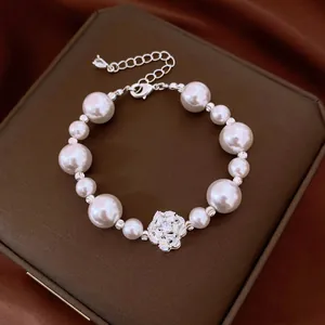 Detailed view of an elegant pearl bracelet with a sparkling zircon flower charm.