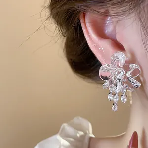 Close-up detail of elegant zircon and resin flower tassel earrings worn on a model's ear