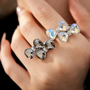 Detailed close-up of sparkling crystal bowknot open rings on hand with elegant accents