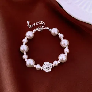 Elegant vintage-style pearl bracelet with a sparkling zircon flower on a deep red fabric background