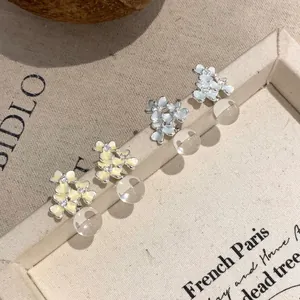 Macro detail of delicate floral stud earrings with rhinestones and clear resin beads