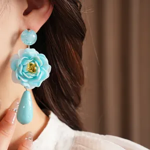 Nahaufnahme eleganter hellblauer Harz-Blumenohrringe mit einem zarten Tropfenanhänger-Anhänger
