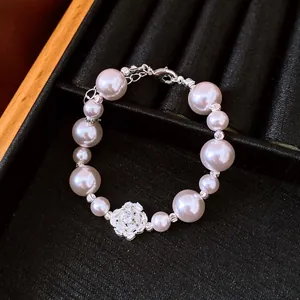 Detail of an elegant pearl bracelet with a sparkling zircon flower centerpiece.