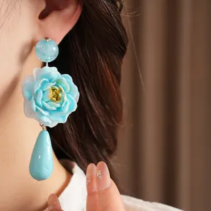 Nahaufnahme von eleganten blauen Verlaufs-Resin-Blütenohrringen mit Quastenanhänger