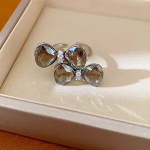 Close-up view of a double bowknot open ring with dark crystals and pavé diamonds.