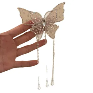 Elegant butterfly hair clip with sparkling rhinestones and long pearl tassels held by hand.