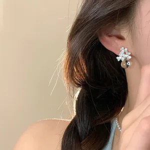 Close-up of elegant flower stud earrings with pearls and rhinestones on model