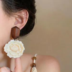 Macro shot of elegant resin flower earrings with wood accents on an Asian female model