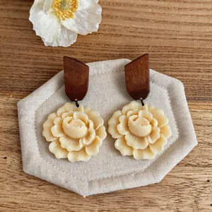 Detailed view of handmade wood and resin flower stud earrings on a linen display mat