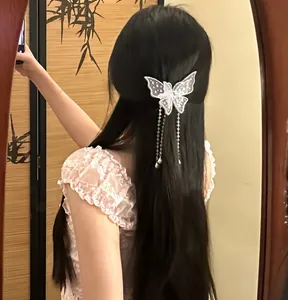 Detail of a white lace butterfly hair clip with shimmering rhinestones and long pearl tassels.