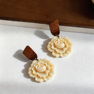 Detailed macro view of cream resin flower earrings with elegant dark wood stud tops