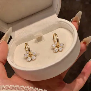 Dettaglio macro di orecchini placcati oro 14k con pendenti a fiore in zircone lucido