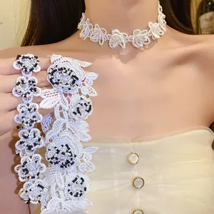 Detail view of a white lace flower choker necklace with delicate black and white beadwork