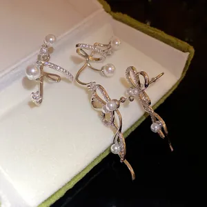 Vista ravvicinata dettagliata di eleganti orecchini ear cuff in zircone e perle in una scatola