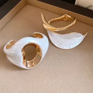 Macro detail of vintage gold plated bangles with white enamel finish and pleated texture.