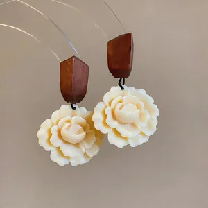 Detailed macro view of elegant cream resin flower earrings with geometric wood accents