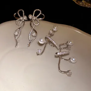 Primo piano squisito di earcuff in zircone e perla scintillanti su un piatto elegante