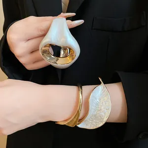 Close-up of elegant gold-toned bracelet with white pleated petal texture worn on wrist