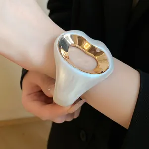 Close-up of elegant white pearlescent resin cuff bracelet with gold-tone metal inlay
