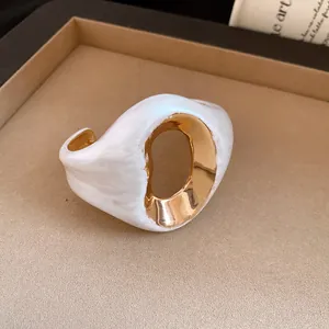 Macro view of a vintage white marble resin and gold-plated irregular cuff bracelet.