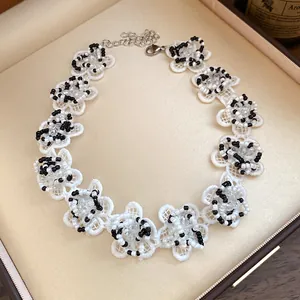 Close-up of white lace flower choker with black glass beads in a luxury gift box