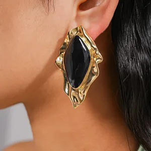 Nahaufnahme von unregelmäßigen geometrischen Goldohrringen mit schwarzer Emaille