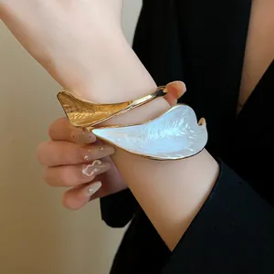 Close-up view showing the textured pleated leaf design of this vintage gold and white bangle.