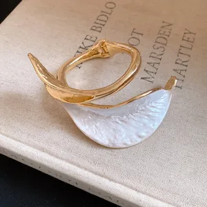 Detailed macro view of vintage gold open bracelet featuring a white pleated petal design