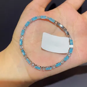 Detail view of an elegant blue rectangular zircon bracelet held in a palm with a silver clasp.