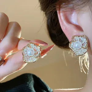 Detail view showing the intricate 18K gold plated floral design with a central pearl