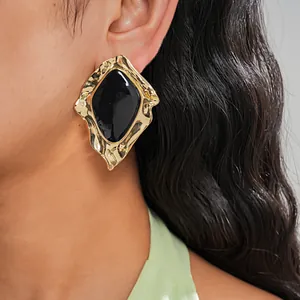 Nahaufnahme von Vintage-Ohrsteckern in Goldoptik mit schwarzer Emaille und Hammerschlag.