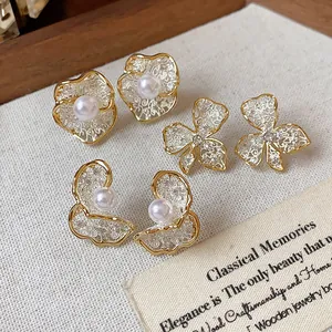 Detailed view of vintage-inspired flower and pearl stud earrings with 18K gold plating