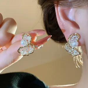 Macro detail of elegant 18K gold plated butterfly earrings with pearls worn on the ear
