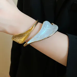 Detailed view of an elegant retro gold and white textured flower petal open bangle