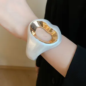 Detail of a vintage pearlescent white flower-shaped open bangle with gold metal inlay