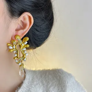 Primo piano di orecchini vintage francesi in oro con strass e dettagli bianchi