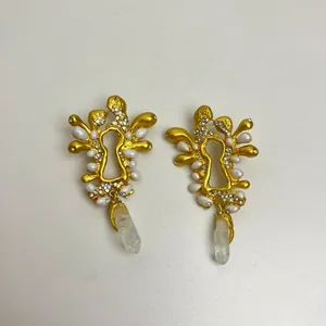 Dettaglio di orecchini vintage in oro a forma di serratura con perle e cristalli