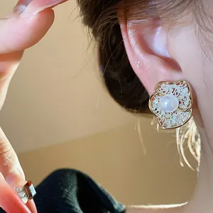 Detail showing an elegant 18K gold plated flower earring with a central pearl inlay