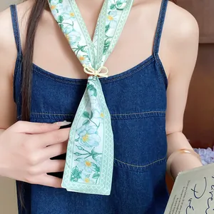 Close-up detail of a mint green floral print skinny fabric scarf with a wooden buckle
