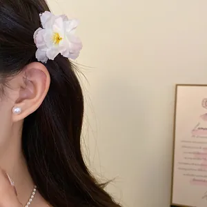 Close-up of an elegant pink and white flower hair clip styled on a model's hair